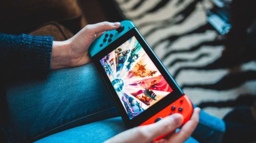 A woman plays a game on a Nintendo Switch handheld gaming console.